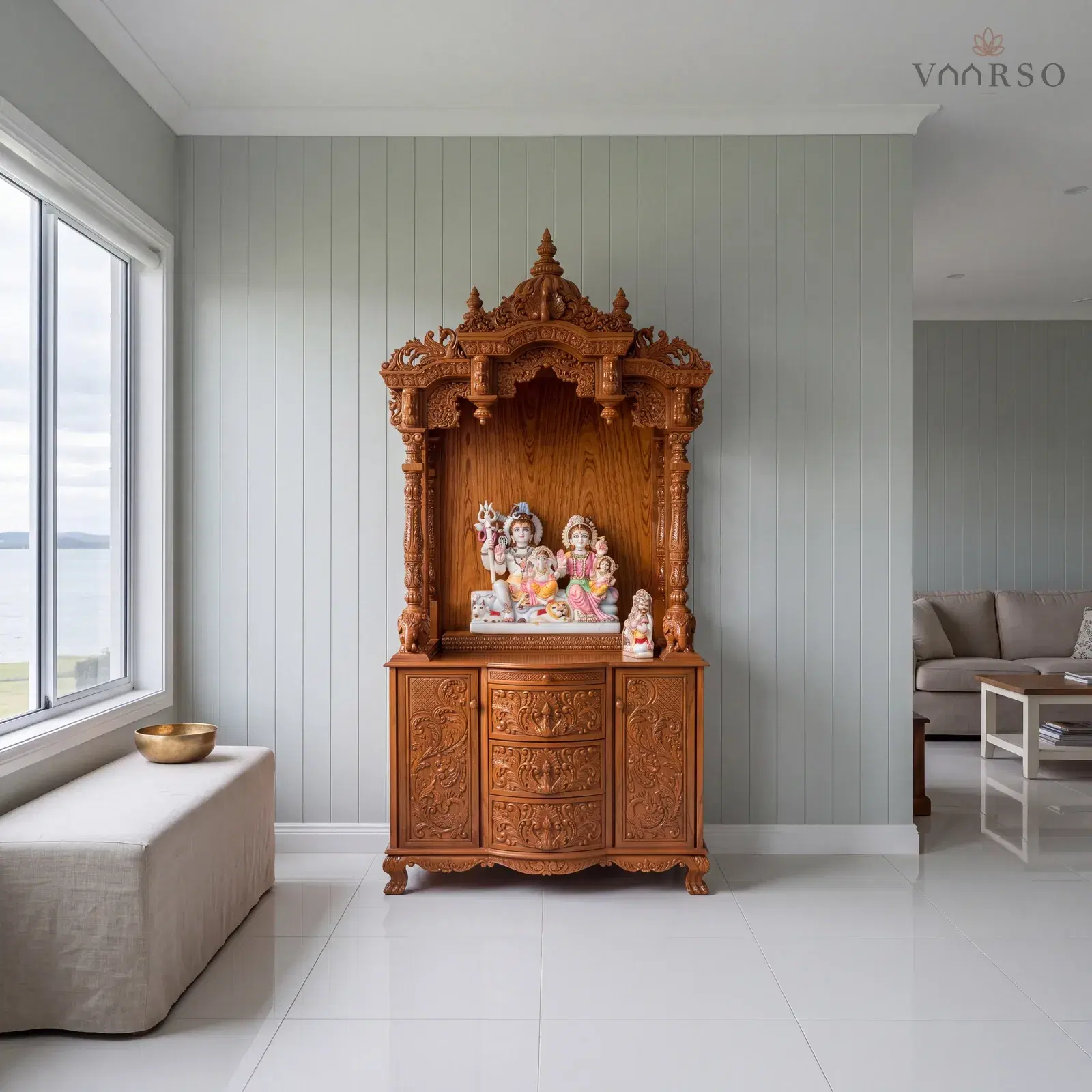 The same mandir in a coastal living room, VJ board panelling behind it, white porcelain tile underfoot and a linen-covered bench carrying a single brass bowl
