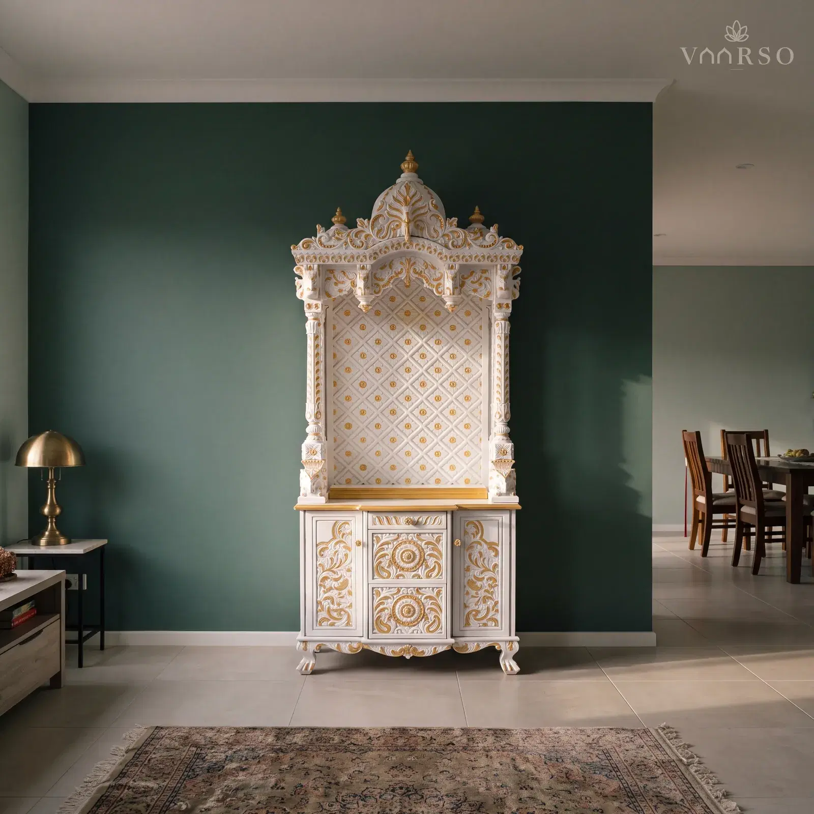 The same mandir in the dining end of an open-plan room, the table well away at the far side, sand-toned porcelain tile underfoot and a worn Persian rug and a brass lamp on a side table
