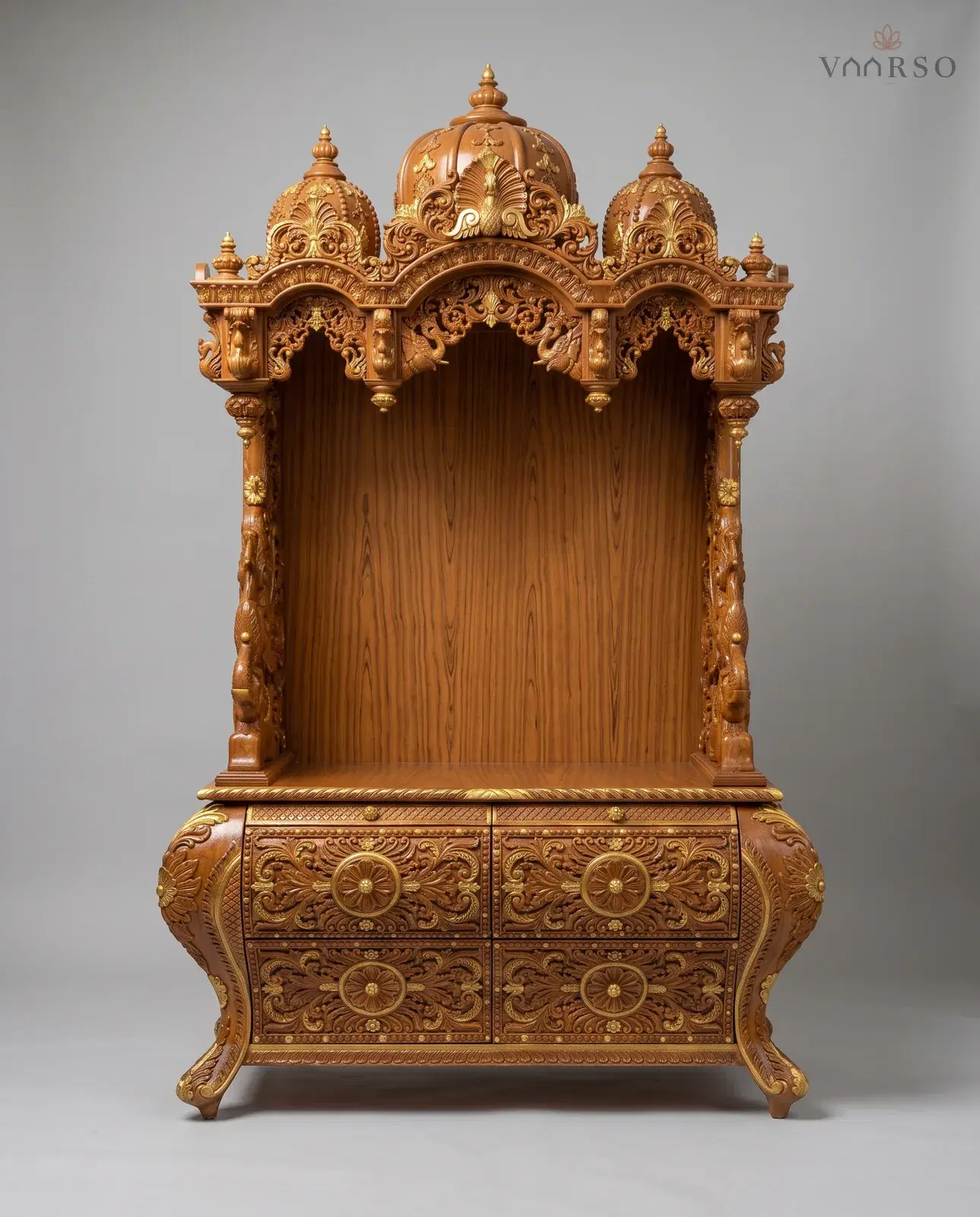 A mandir in a warm natural polish picked out in gold, three domes with a peacock at the centre, an empty shrine on carved columns, and a bow-fronted chest of four deeply carved drawers on cabriole feet