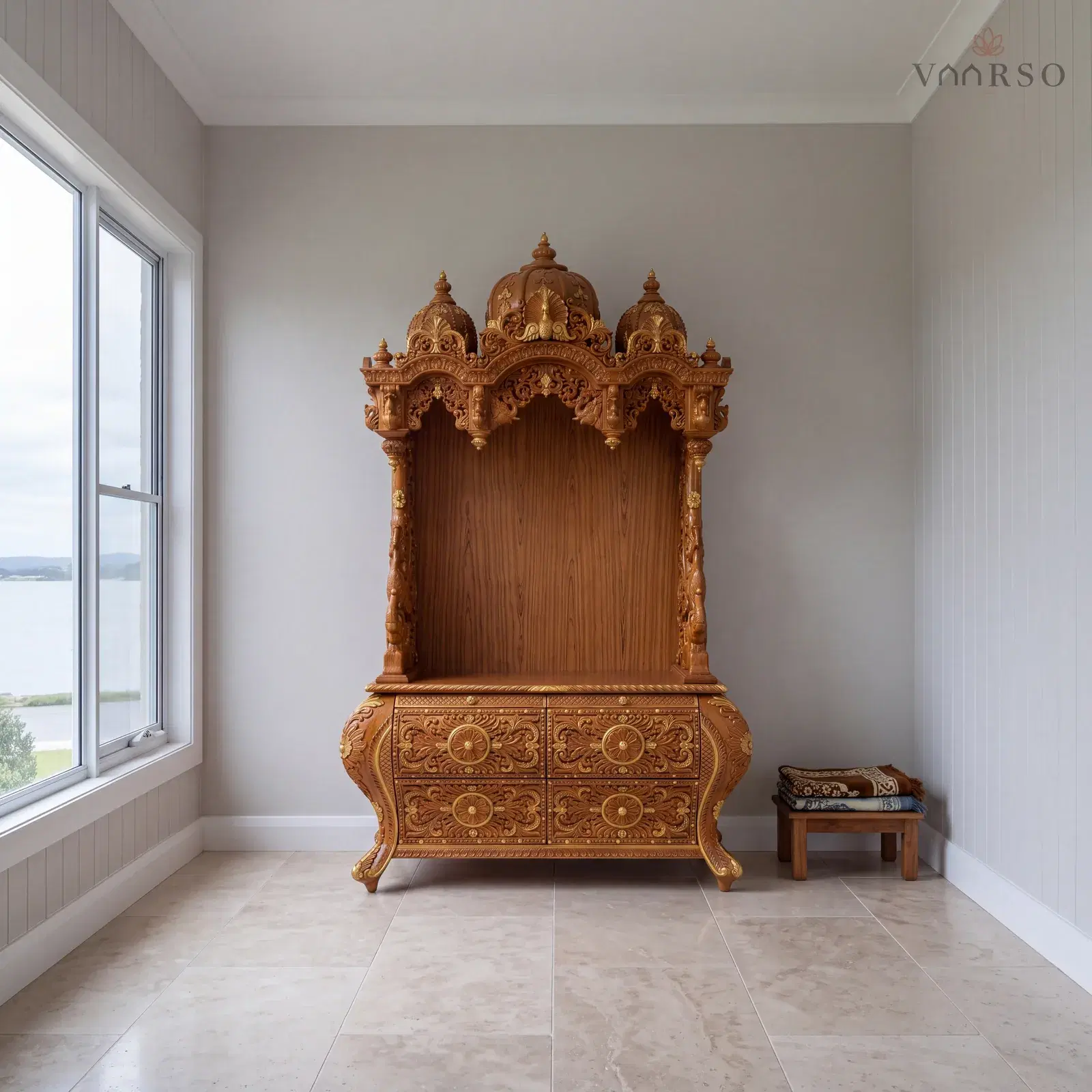 The same mandir in a coastal living room, VJ board panelling behind it, honed travertine underfoot and a pair of folded prayer mats on a low stool