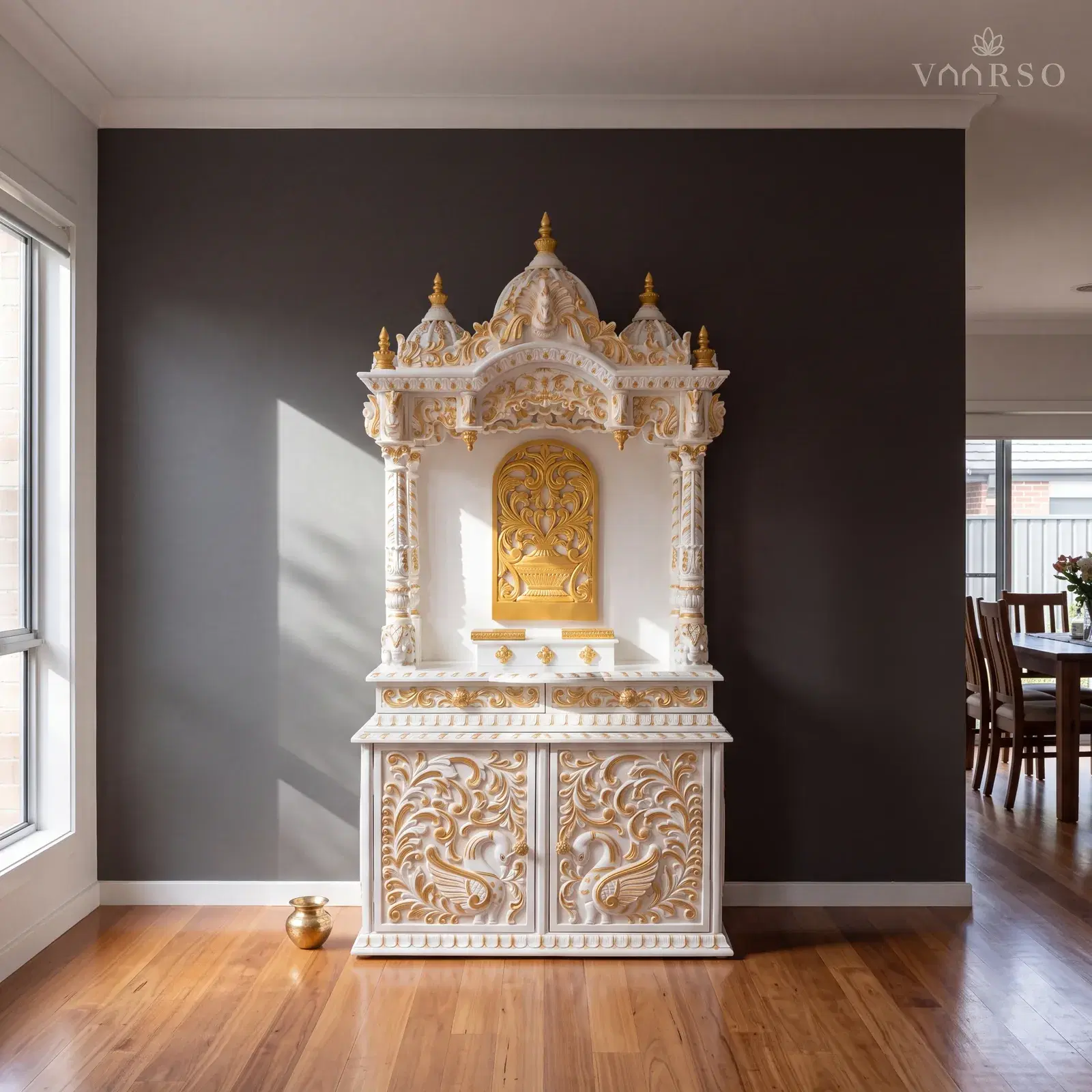The same mandir in the dining end of an open-plan room, the table well away at the far side, blackbutt boards underfoot and a small brass kalash on the floor beside it