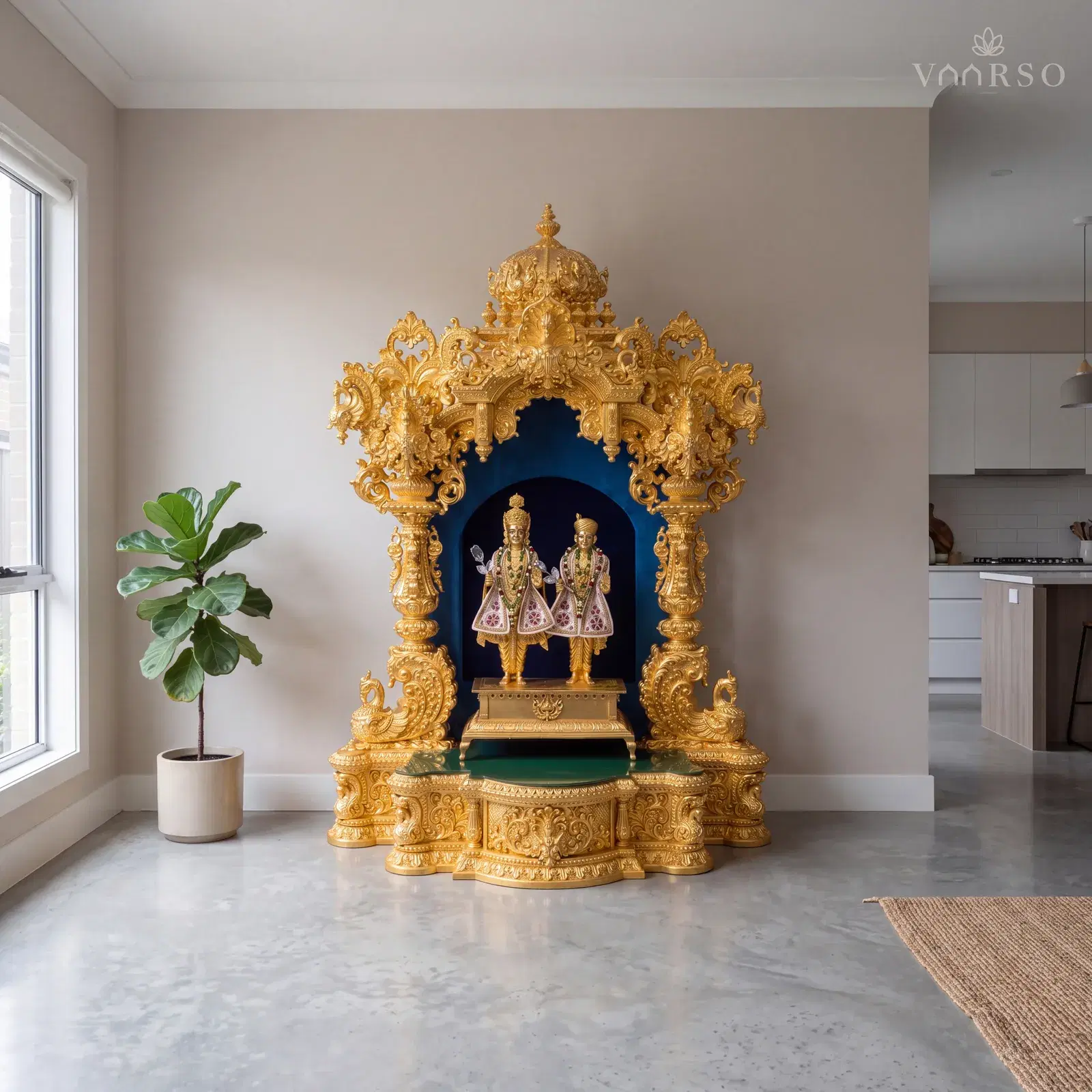 The same mandir in the edge of an open-plan living space, the kitchen away at the far end, polished concrete underfoot and a fiddle-leaf fig in a ceramic pot to one side
